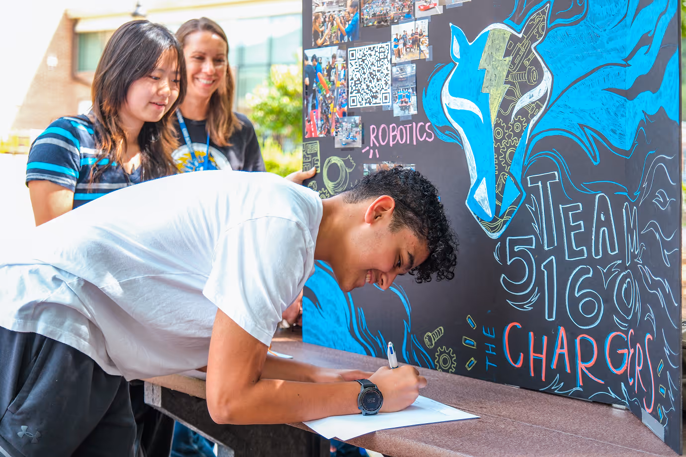 Cary Academy student signing up for robotics club at school club fair event showcasing Charger spirit and teamwork.