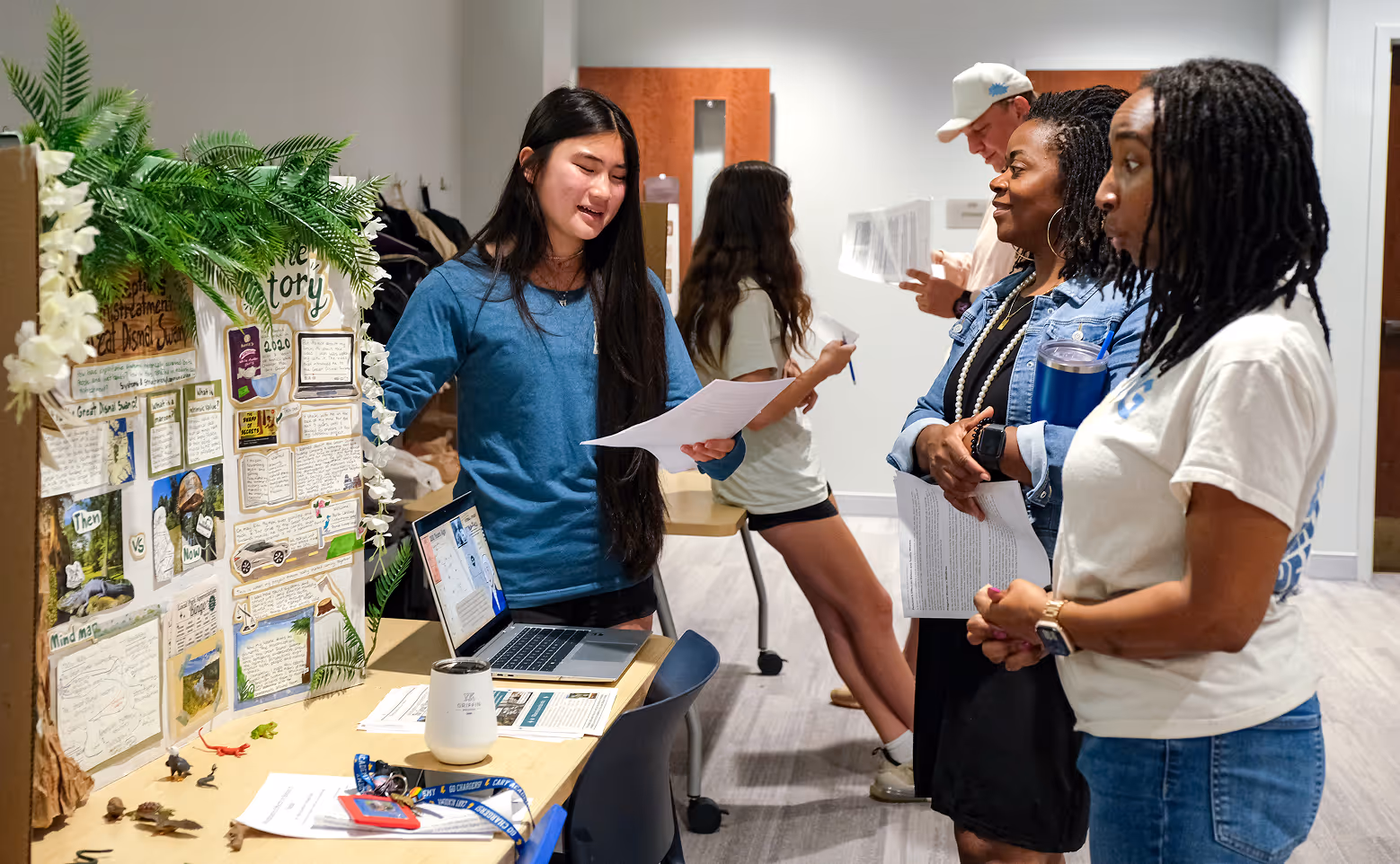 Student presenting 8th Grade Capstone project at Cary Academy, discussing research findings with teachers and parents.