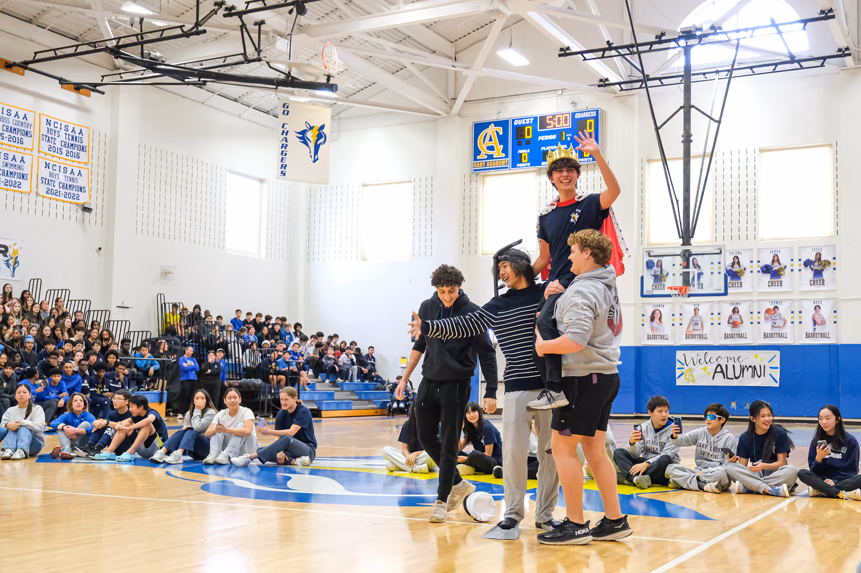 Cary Academy students performing a fun skit during Winter Pep Rally in the school gym with classmates cheering.