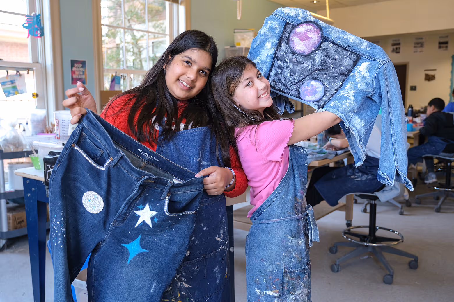 Cary Academy middle school students proudly displaying their painted denim art projects during X-Day creative workshop.