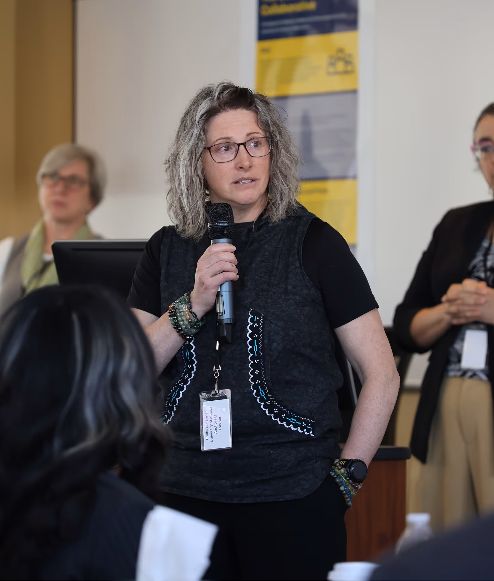 Faculty member speaking into a microphone during a presentation.