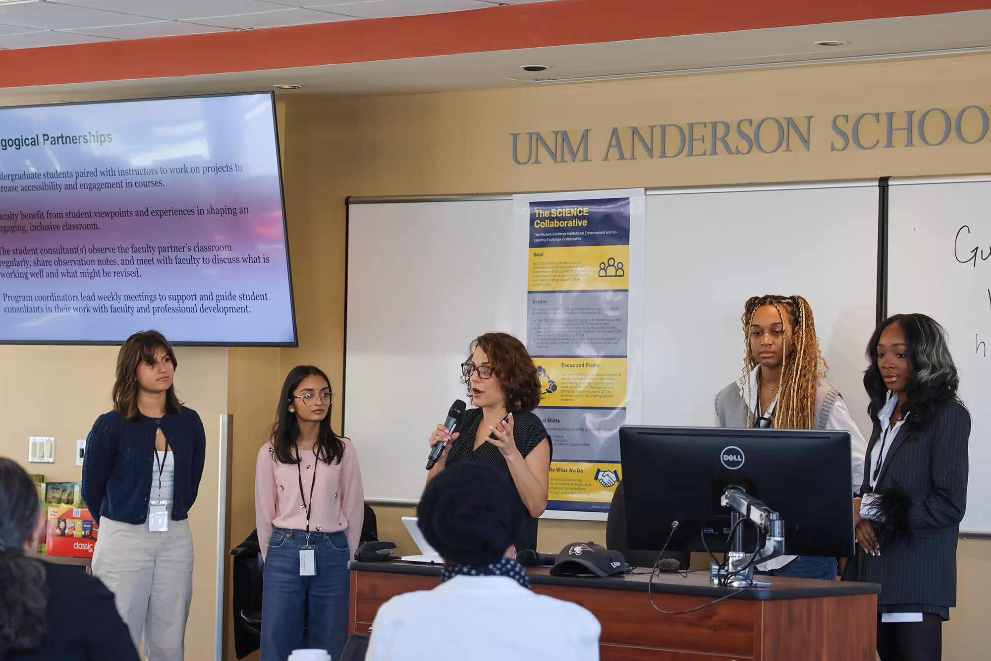 A faculty member speaking in front of a group in a workshop meeting