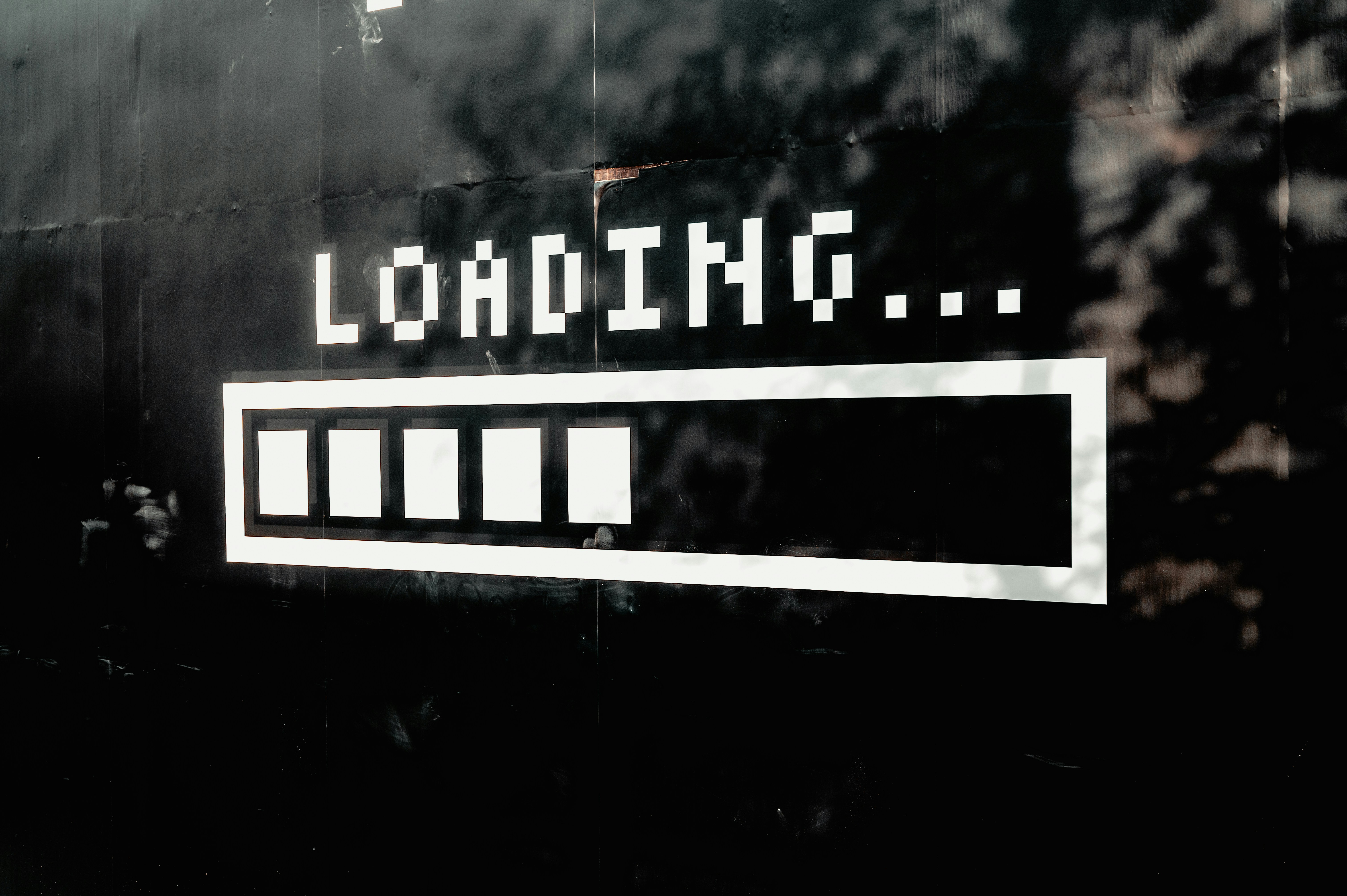 Black wall with white pixelated text 'LOADING...' above a progress bar showing partial loading.