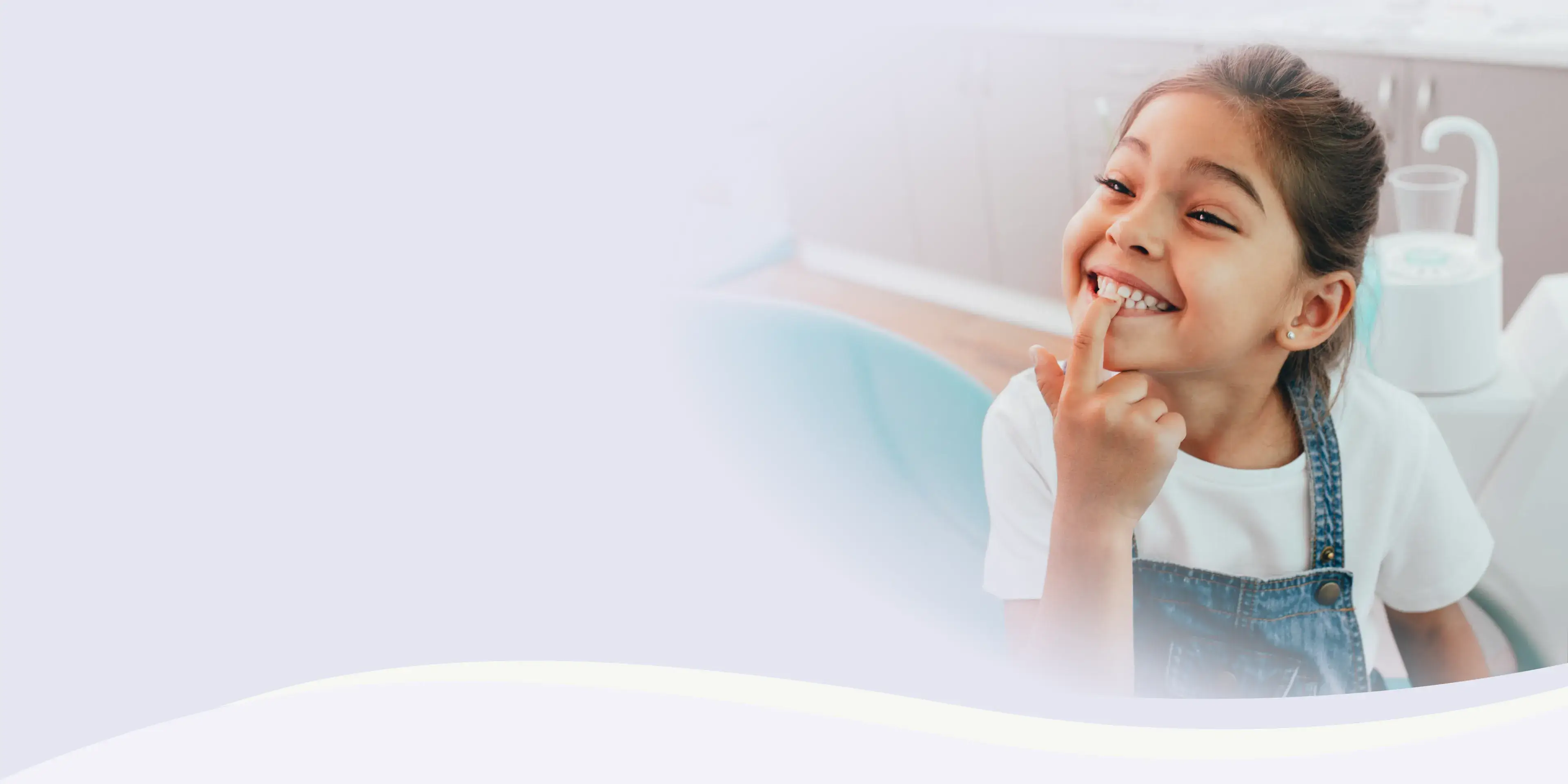 A young girl smiles broadly, showing her teeth while sitting in a dental chair.