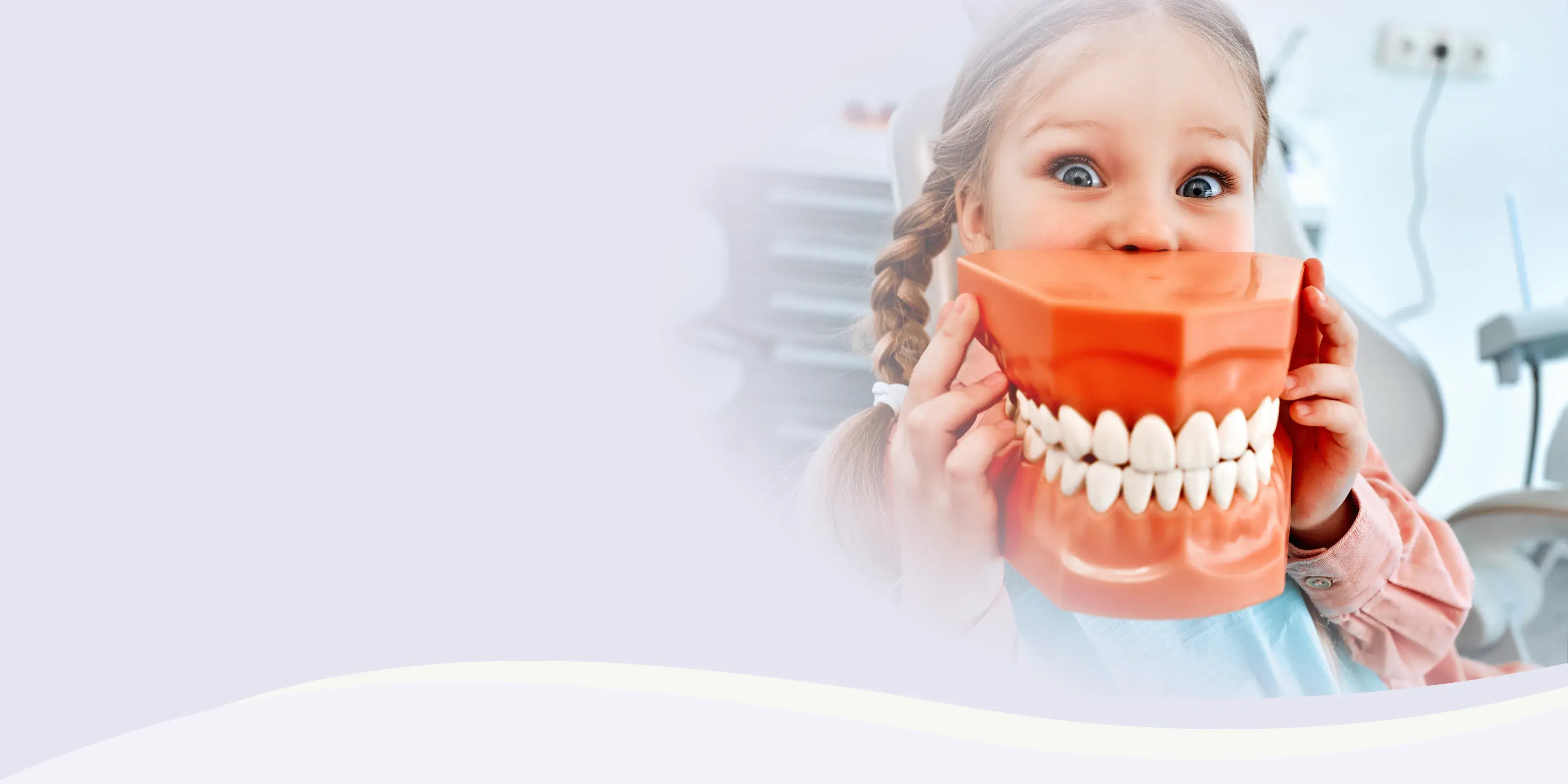 Child holding a large model of teeth and smiling widely.