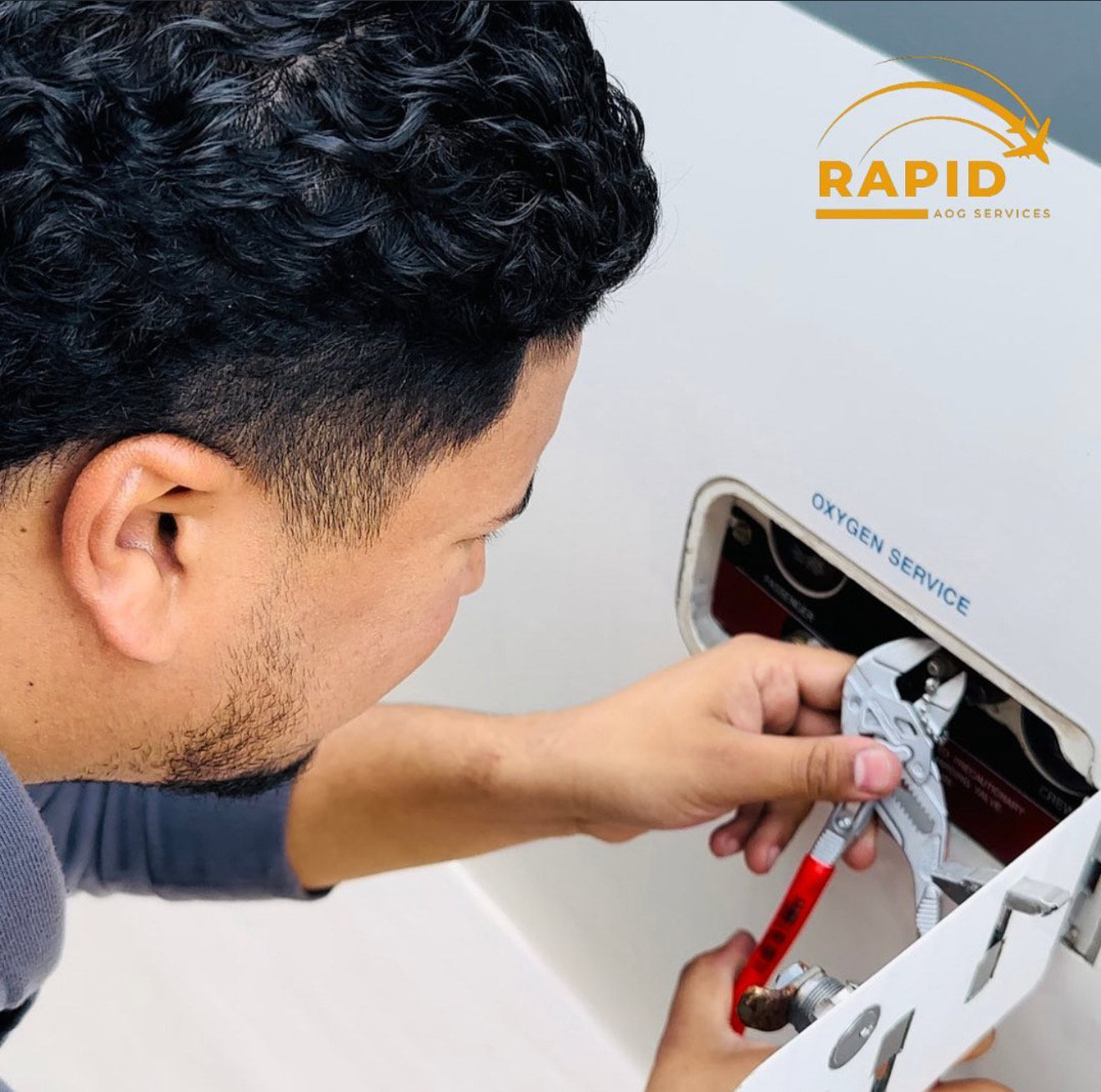 Man using a plier tool to adjust a valve labeled 'Oxygen Service' on a white panel with a Rapid AOG Services logo above.
