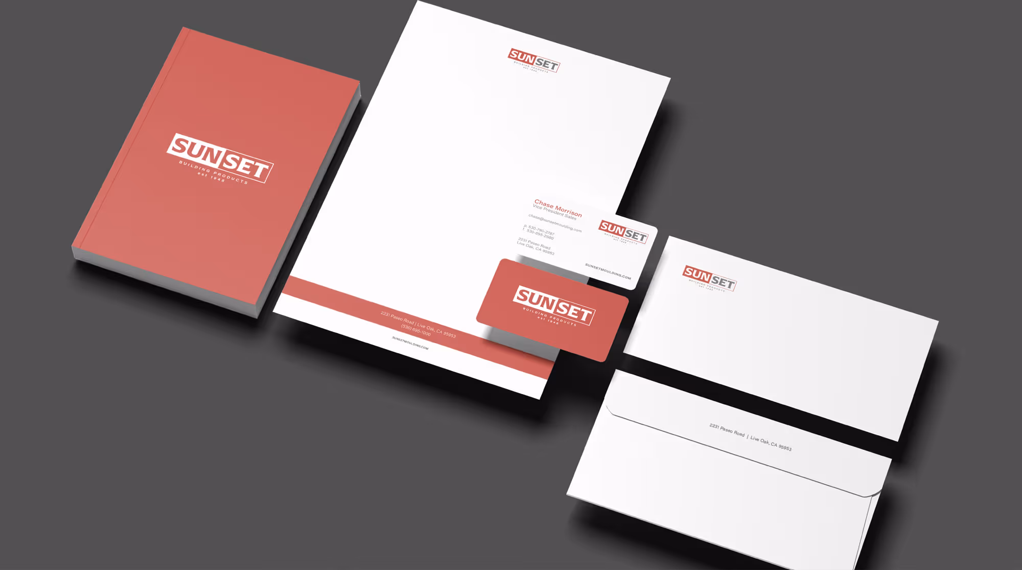 Set of corporate stationery including a red notebook, letterhead, two business cards, and an envelope with the Sunset Building Products logo on a dark background.