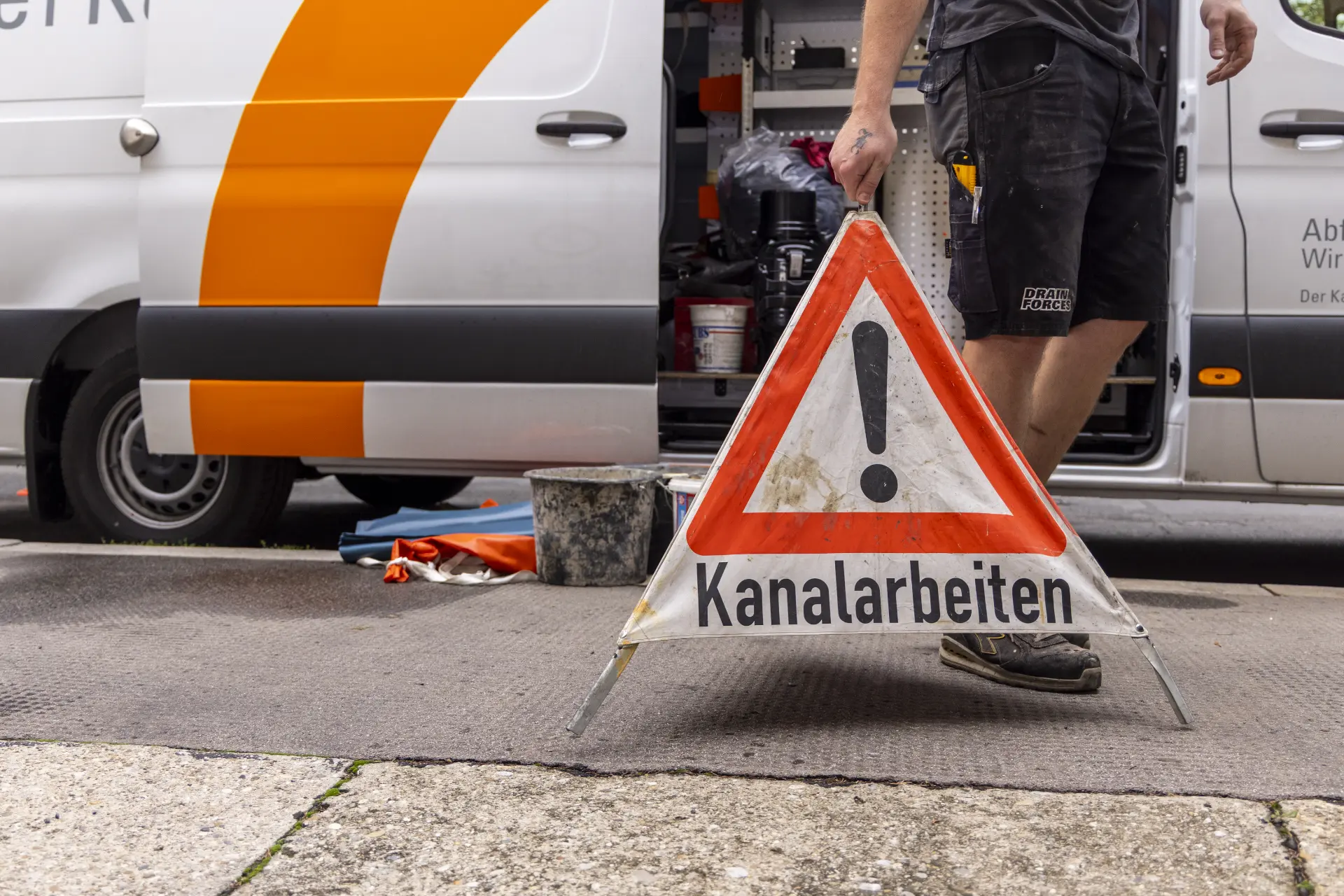 Ein Kanalfacharbeiter sichert die Baustelle ab.