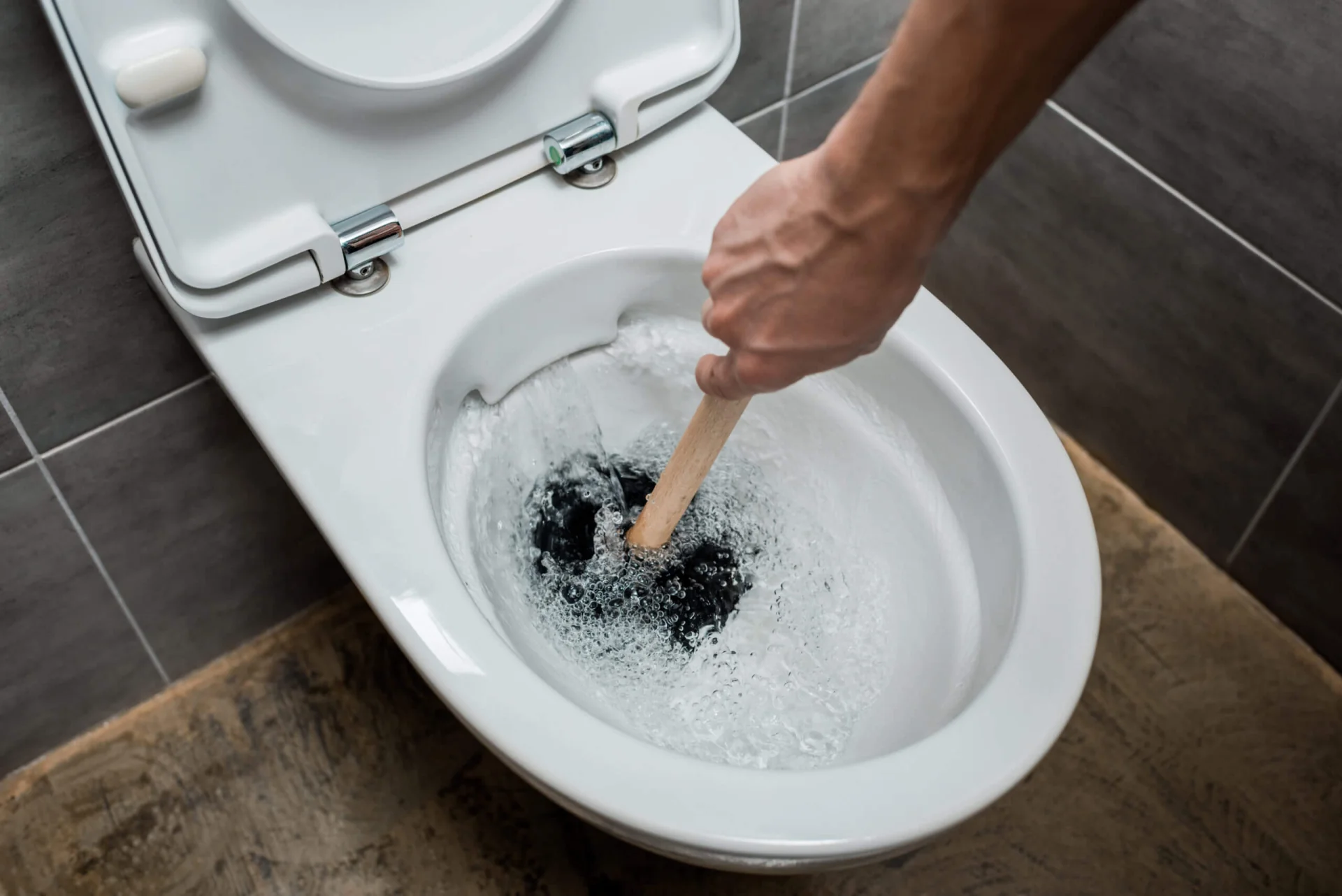 Plumber plunging toilet