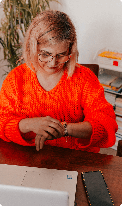 Coach Duszy Ela Rojek siedząca przy biurku wśród kwiatów.