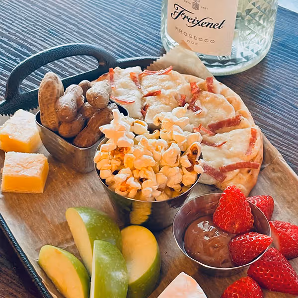 tray with cheese, chocolate strawberry, apples, popcorn, pita, and peanuts