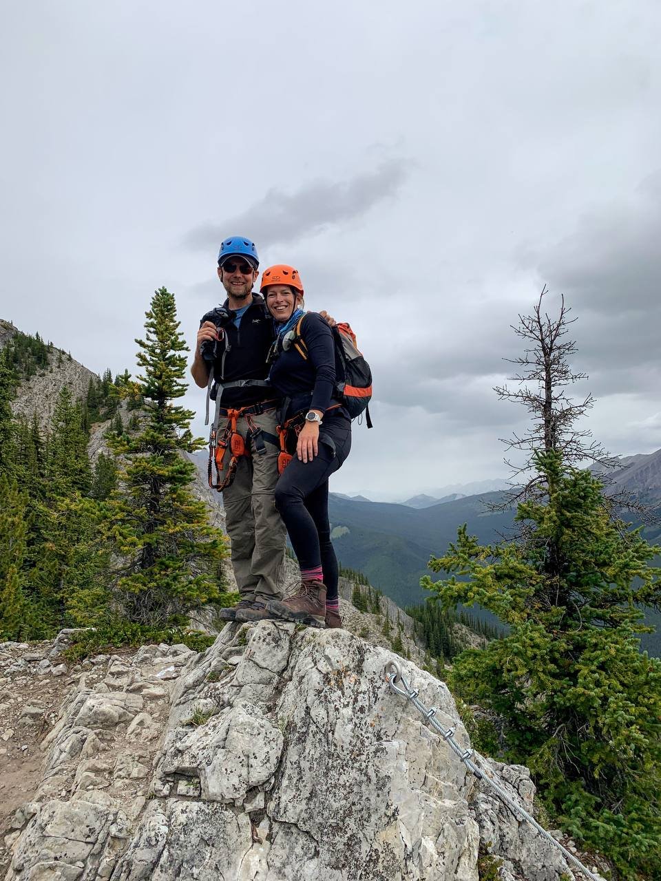 couple smiling while standing on a rock