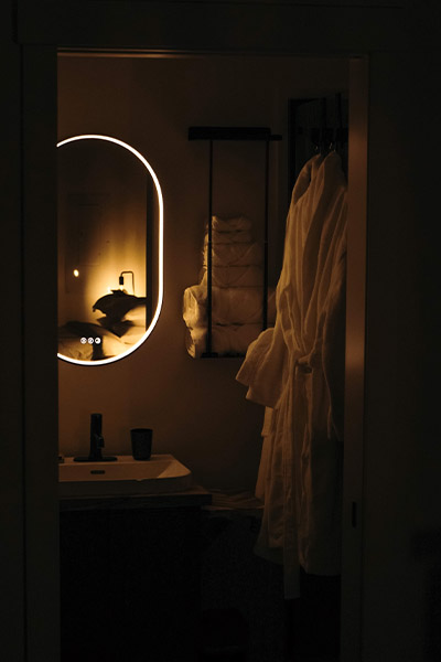 dark bathroom with a lit up mirror