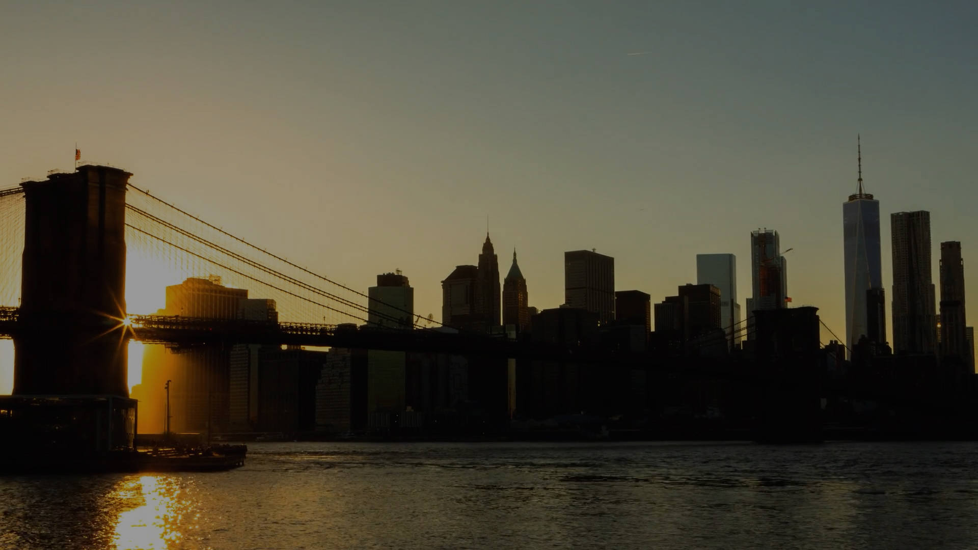 Brooklyn Bridge and Manhattan skyline silhouetted at sunset