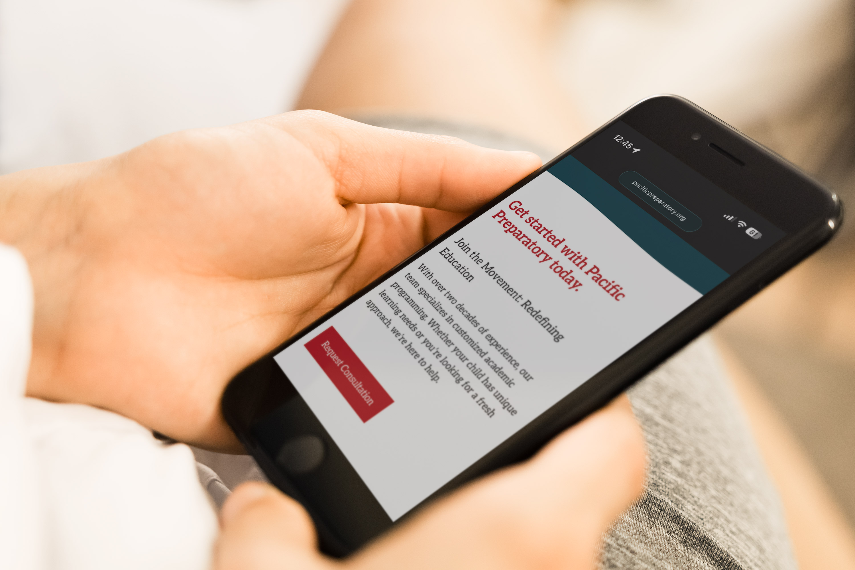 Hands holding smartphone displaying Pacific Preparatory School mobile website