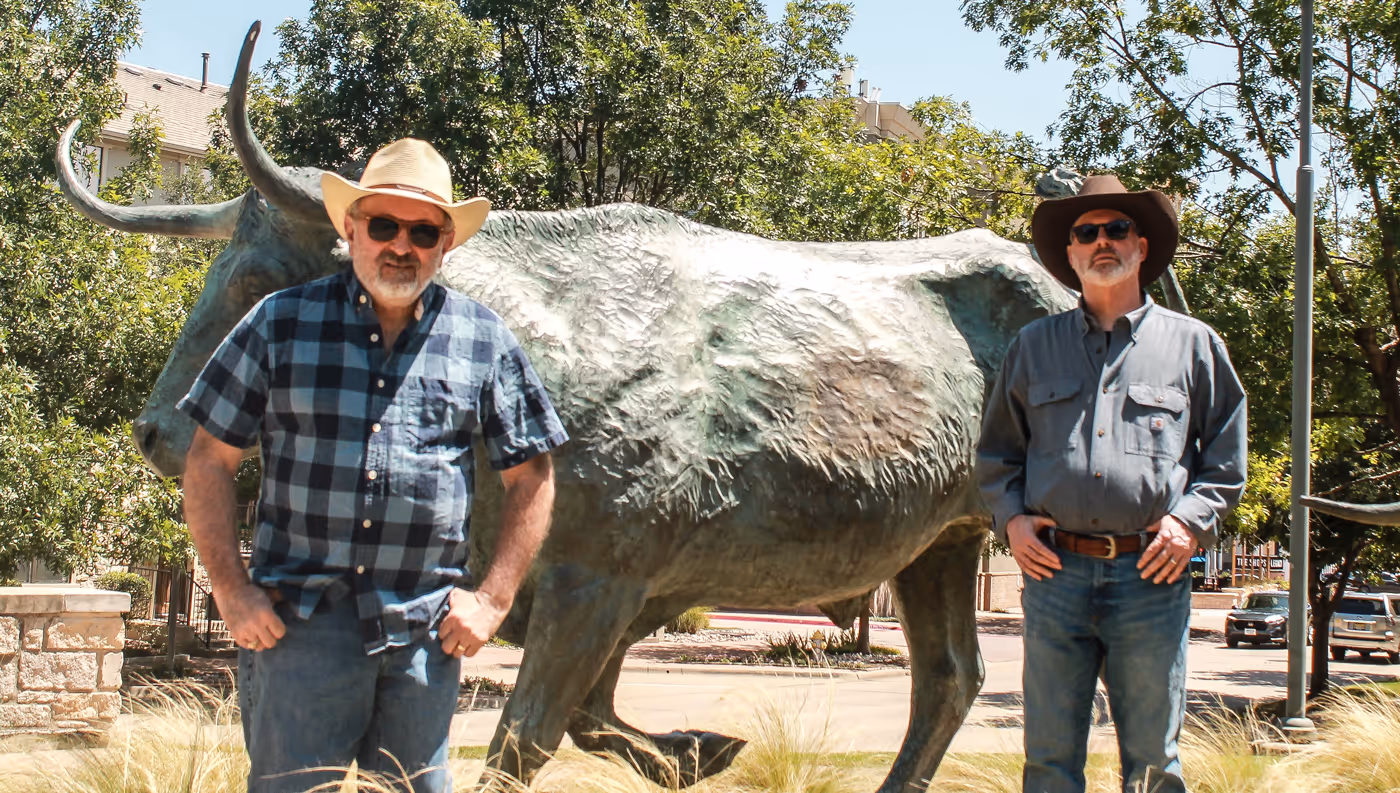Jeff and John in Texas in front of a statue of a long horn bull