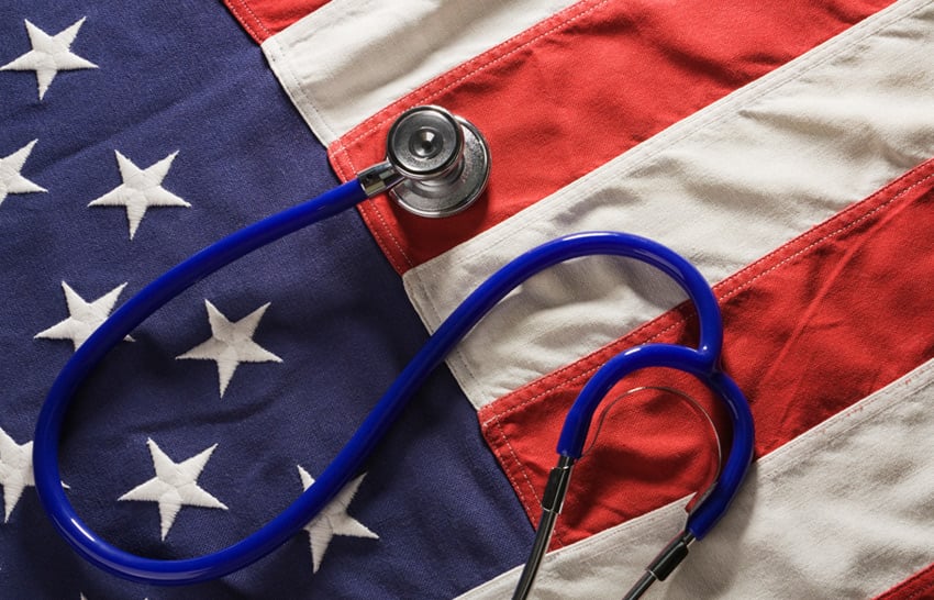 Blue stethoscope lying on an American flag with white stars and red and white stripes.