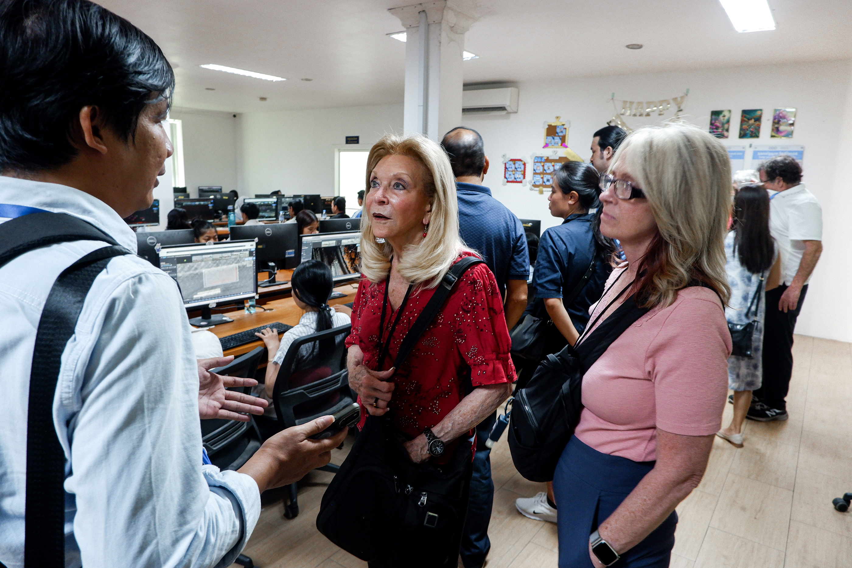 Audience at a panel discussion event on Cambodia's digital future, seated facing a stage with a speaker at a podium and large screens displaying panel information.