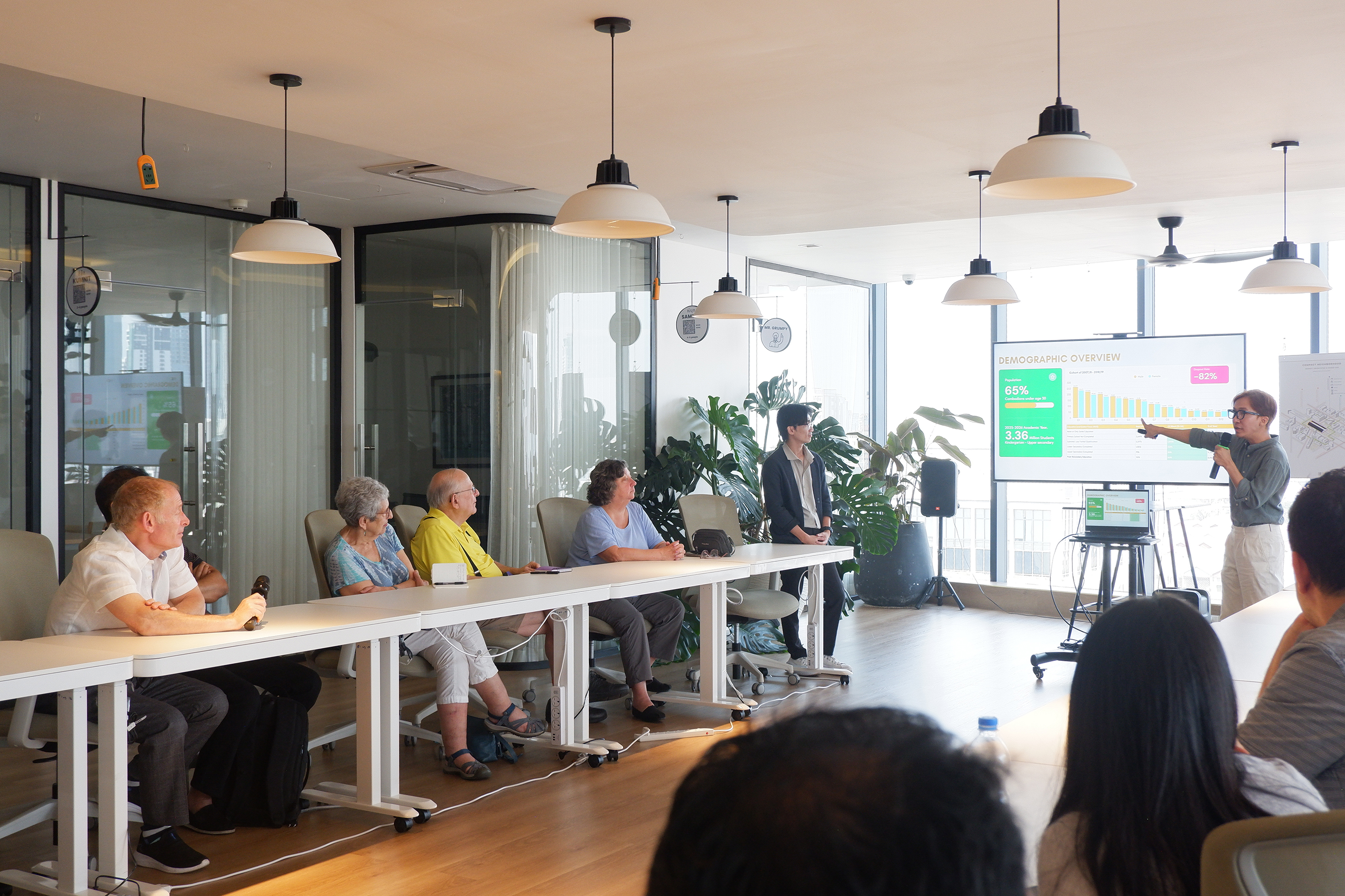 Audience at a panel discussion event on Cambodia's digital future, seated facing a stage with a speaker at a podium and large screens displaying panel information.