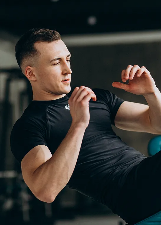 Focused man doing abdominal exercises at the gym, representing enhanced metabolism and fat burning from Erectile Dysfunction Treatment