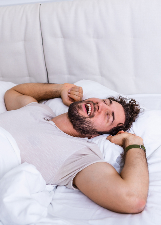 Man waking up refreshed in bed, symbolizing improved sleep and recovery with Vitamin B Complex injections.