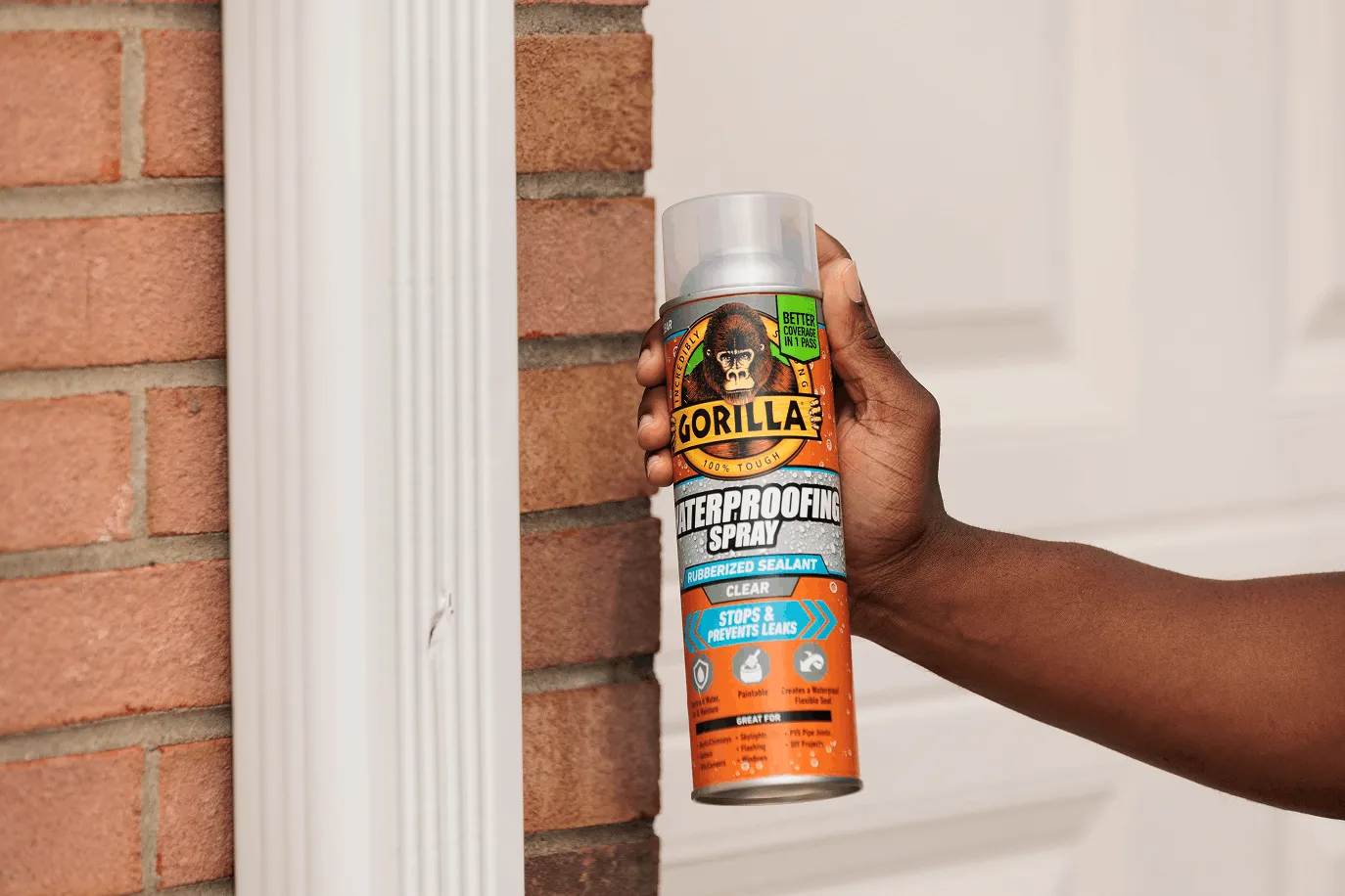 Hand holding a can of Gorilla Waterproofing Spray next to a cracked gutter.