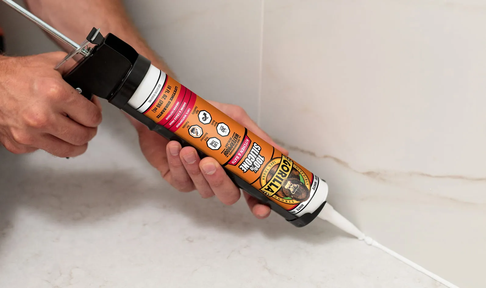 Person applying white Gorilla 100% silicone sealant in a shower.