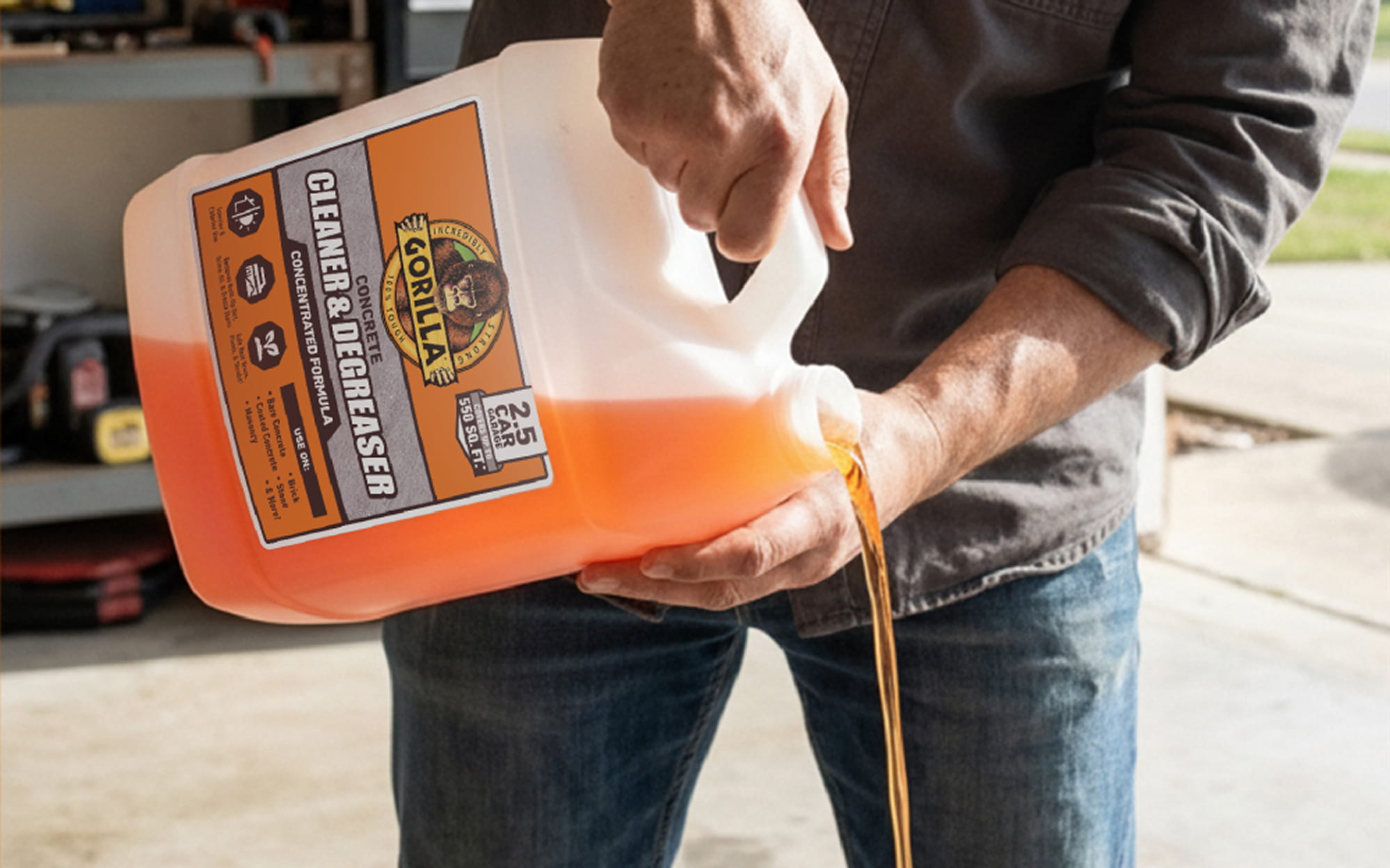 Person pouring orange liquid from a Gorilla Concrete Cleaner & Degreaser jug.