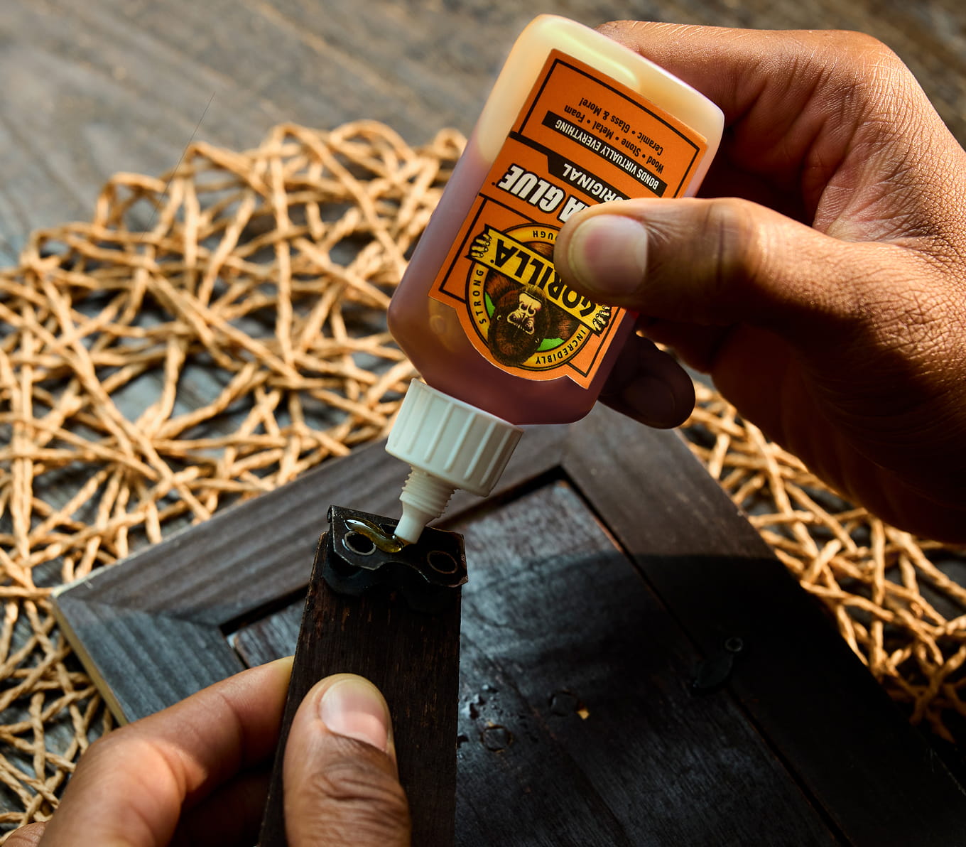 Person applying Gorilla Glue to a dry piece on a picture frame.