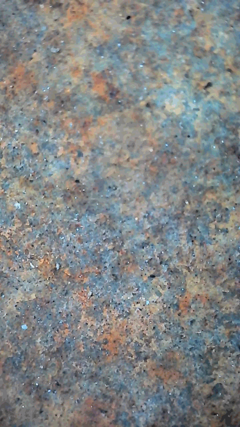 Microscopic view of rust-contaminated steel before laser stripping with coarse surface and embedded particulates