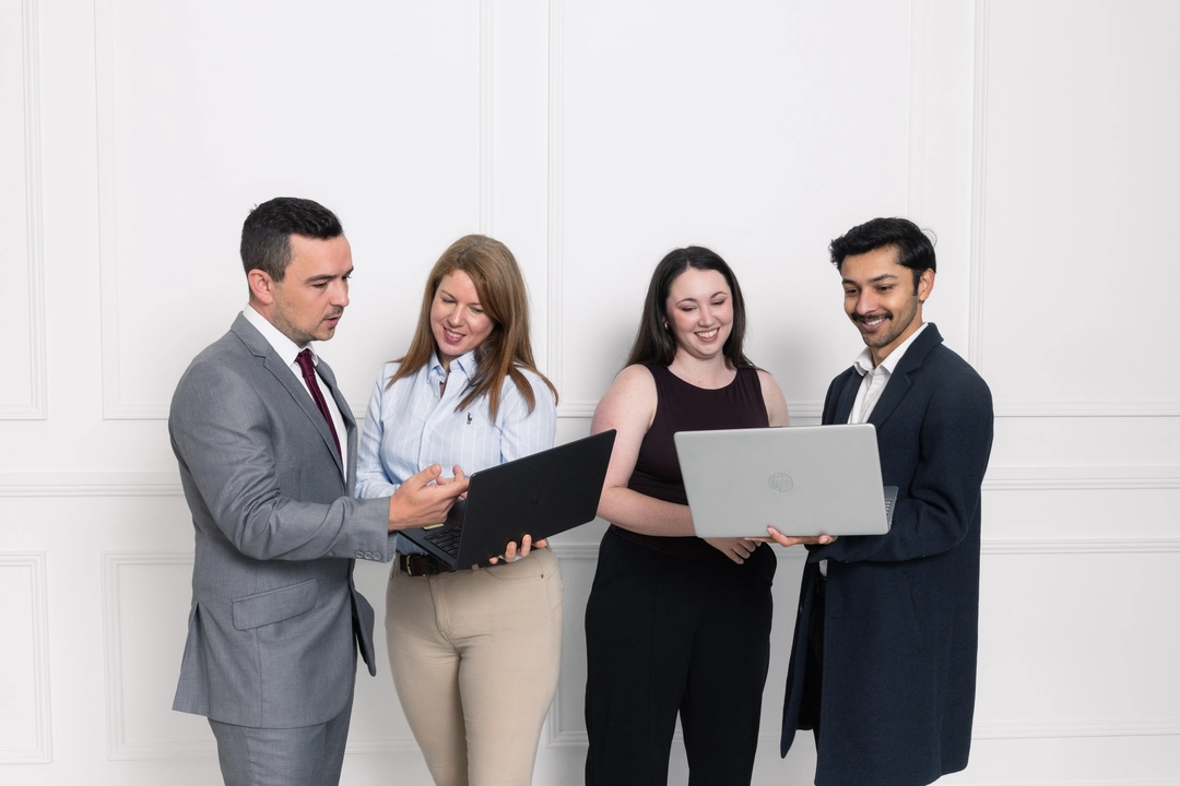 Four professionals having a meeting around a black table in a modern office with a window.