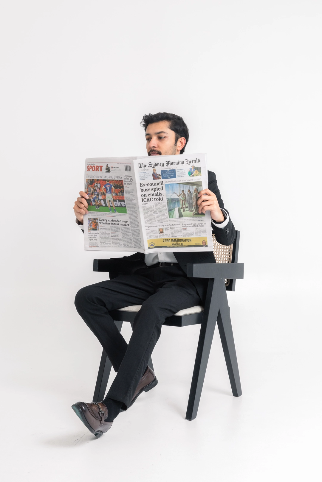 a man sitting in a chair reading a newspaper