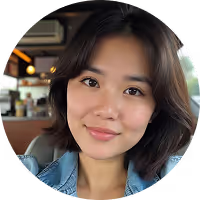 Close-up of a smiling young woman with shoulder-length dark hair wearing a denim jacket in a casual indoor setting.