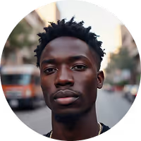 Portrait of a young Black man with short curly hair and a neutral expression, urban street background.
