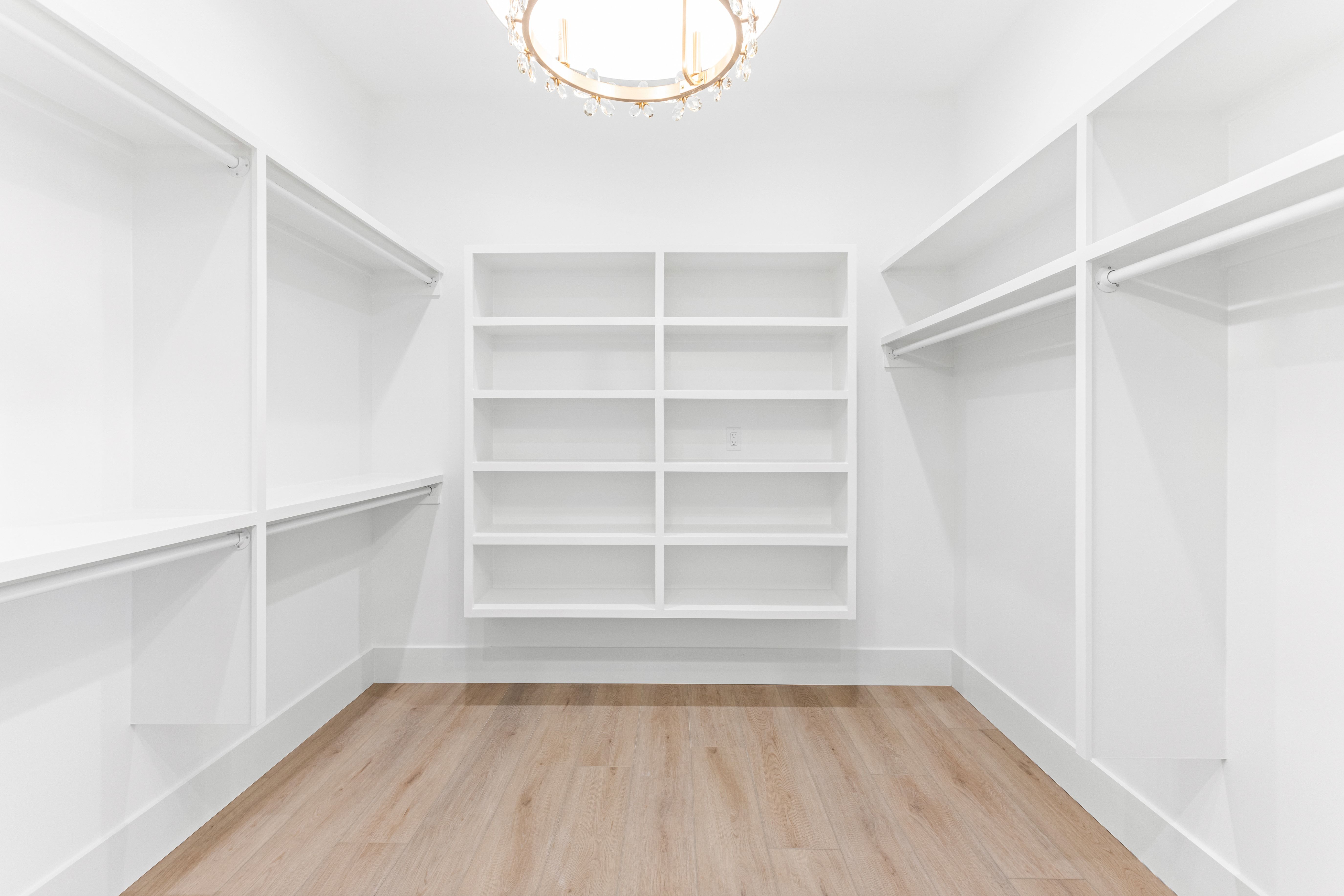 Empty walk in closet with white shelves and a round ceiling light in the New Port custom home, Hampstead, NC