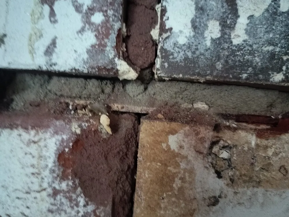 Rapautunut ja aukeava sauma vanhan tiilitakan pinnassa lähikuvassa