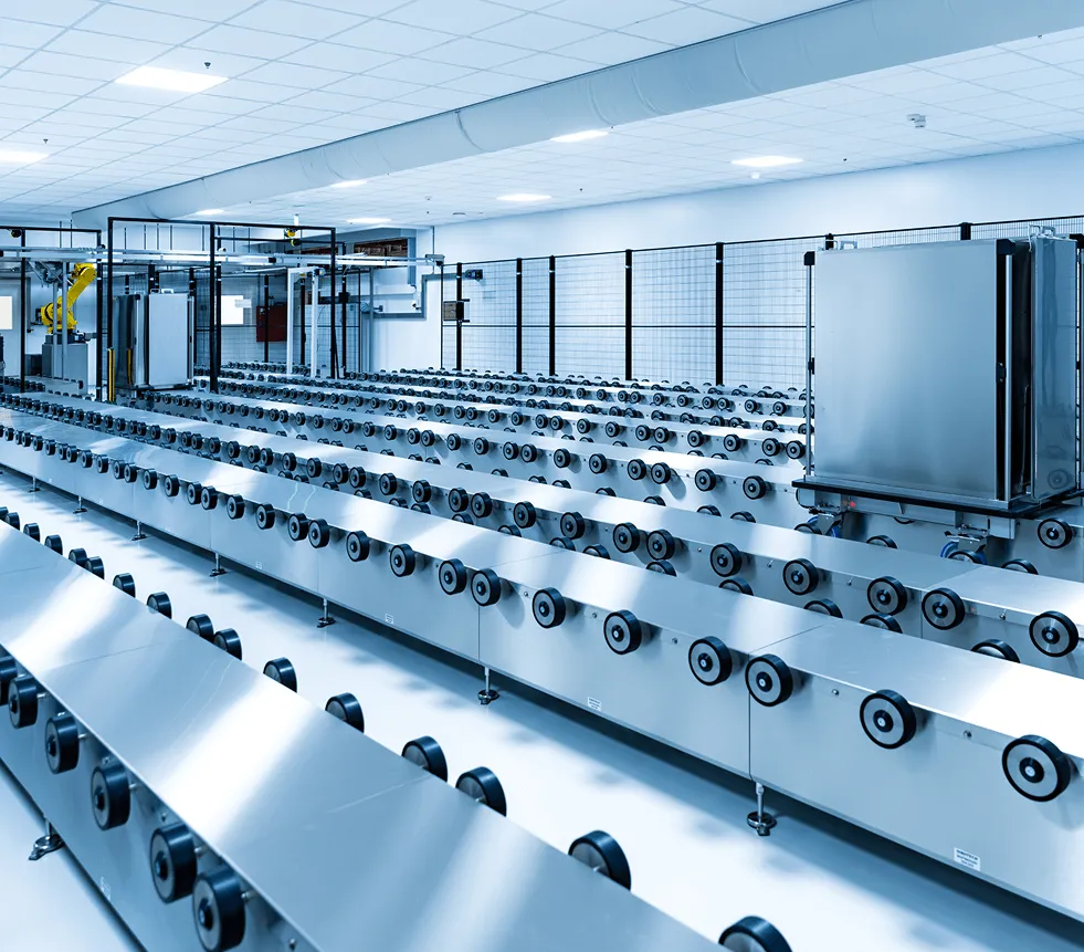 Industrieanlage mit langen Reihen von Metallrollen für den Transport in einer robotergesteuerten Fabrikhalle.