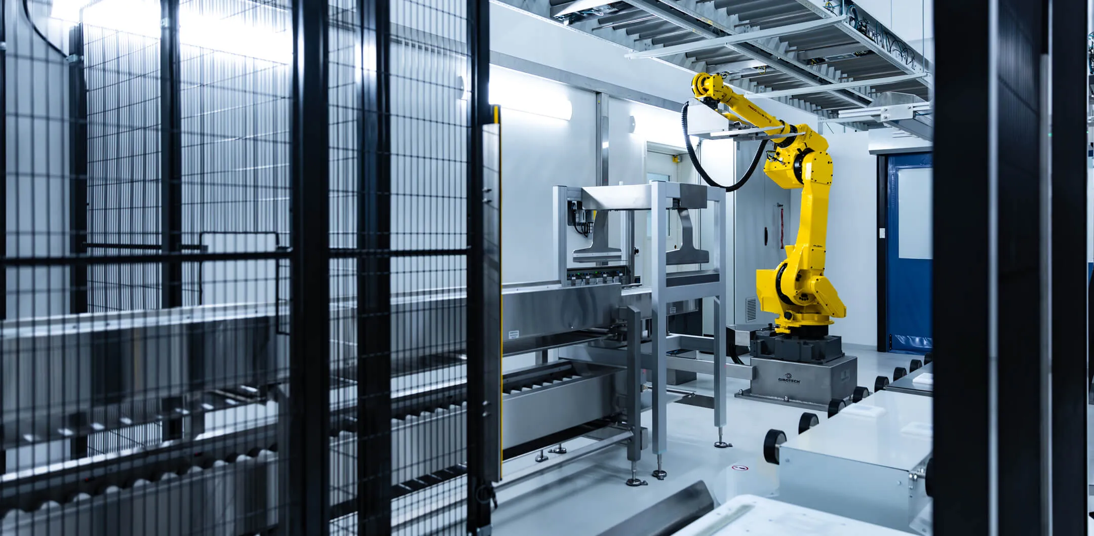 Ein gelber Roboterarm in einer sauberen, modernen Industrieumgebung mit Metallausrüstung und Aufbewahrungsmöbeln.