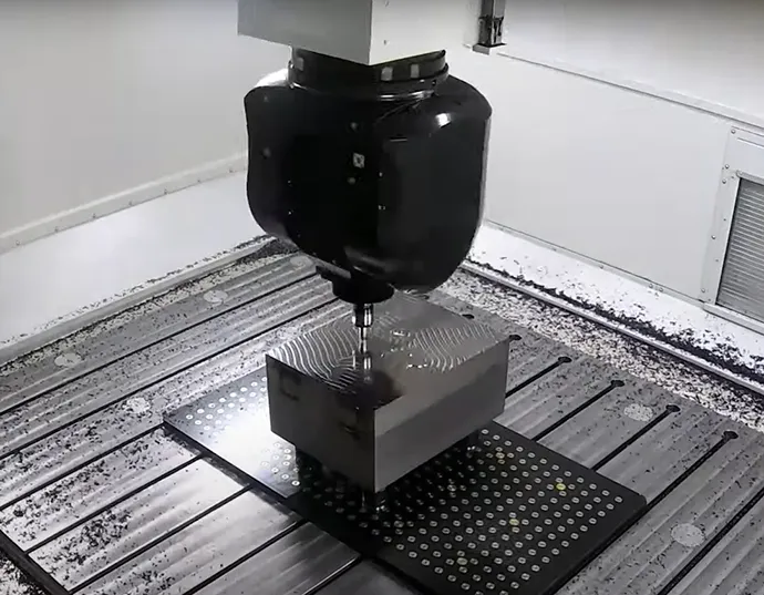 Eine CNC-Maschine schneidet ein Metallstück auf einem Arbeitstisch, um den herum Metallspäne liegen.