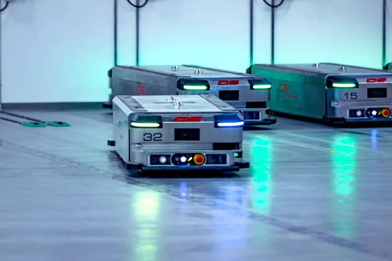 Automatiske lagersystemrobotter nummer 32, 15, og en uden nummer på et lagergulv.