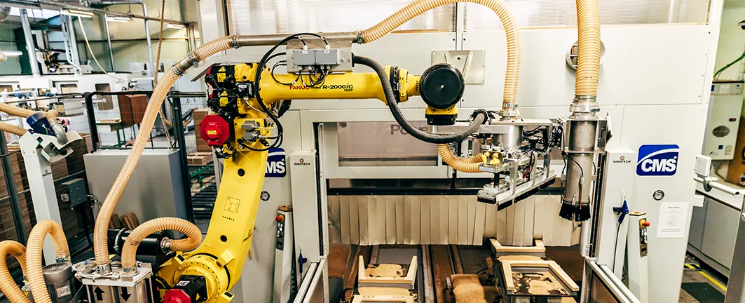 Gule robotter betjener CNC-maskine i automatisk maskinbetjening