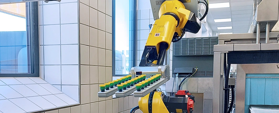 Gul robot håndterer stativ med glas i køkkenautomation til Nyt OUH