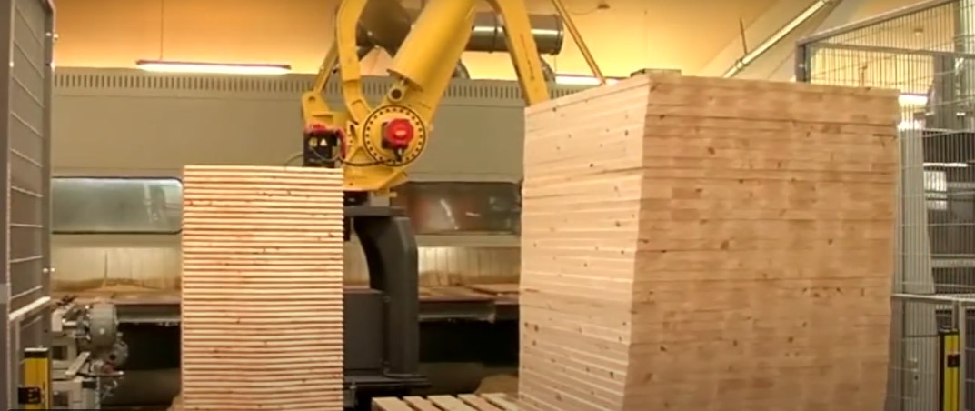 Gul robot stabler træplader ved CNC-maskine på møbelfabrik