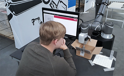Ein junger Mensch programmiert einen Cobot am Computer