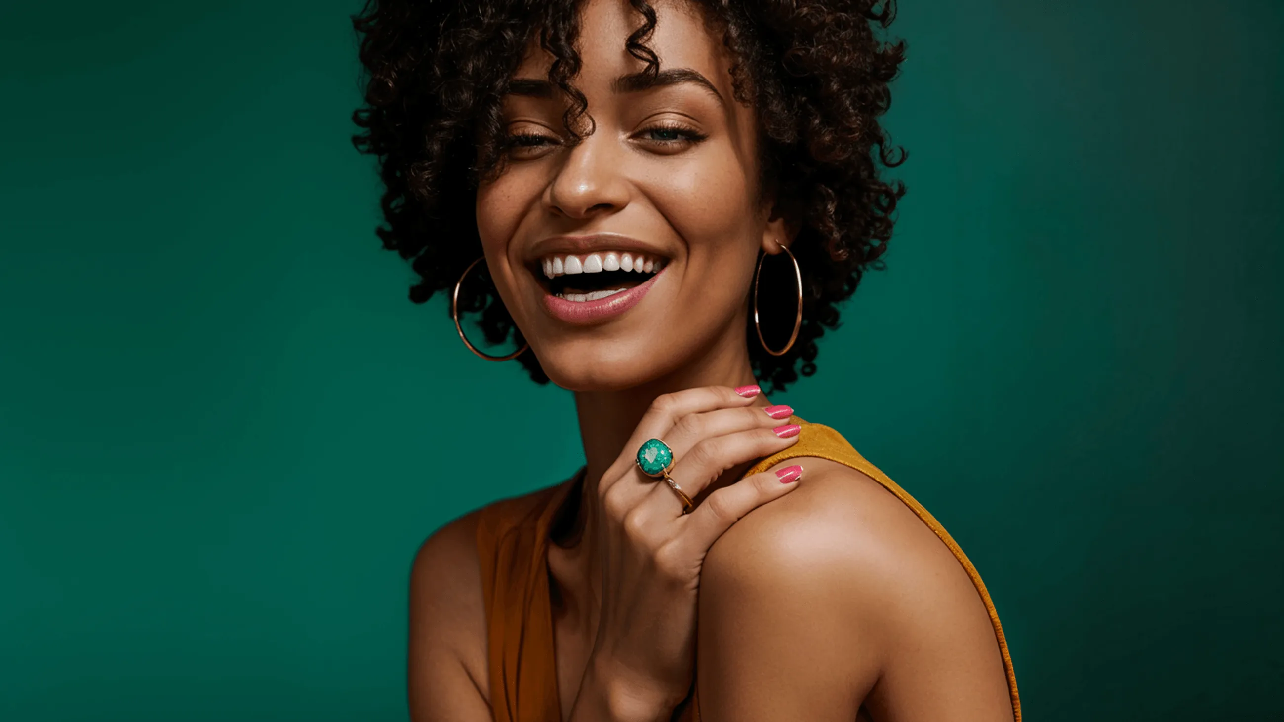 A woman with curly hair smiling and wearing earrings.