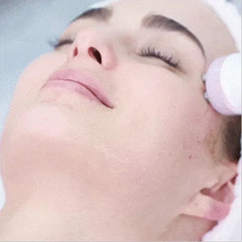 A woman getting a facial massage with a towel on her head.