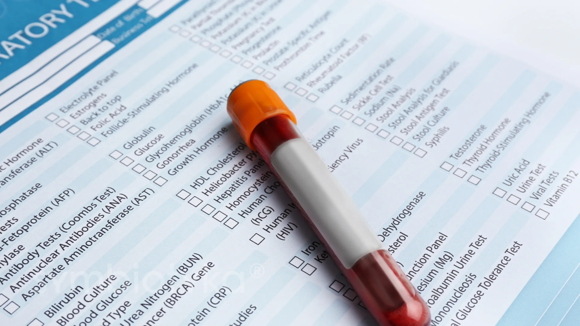 Blood sample vial with an orange cap placed on a medical laboratory test form listing various blood and urine tests.