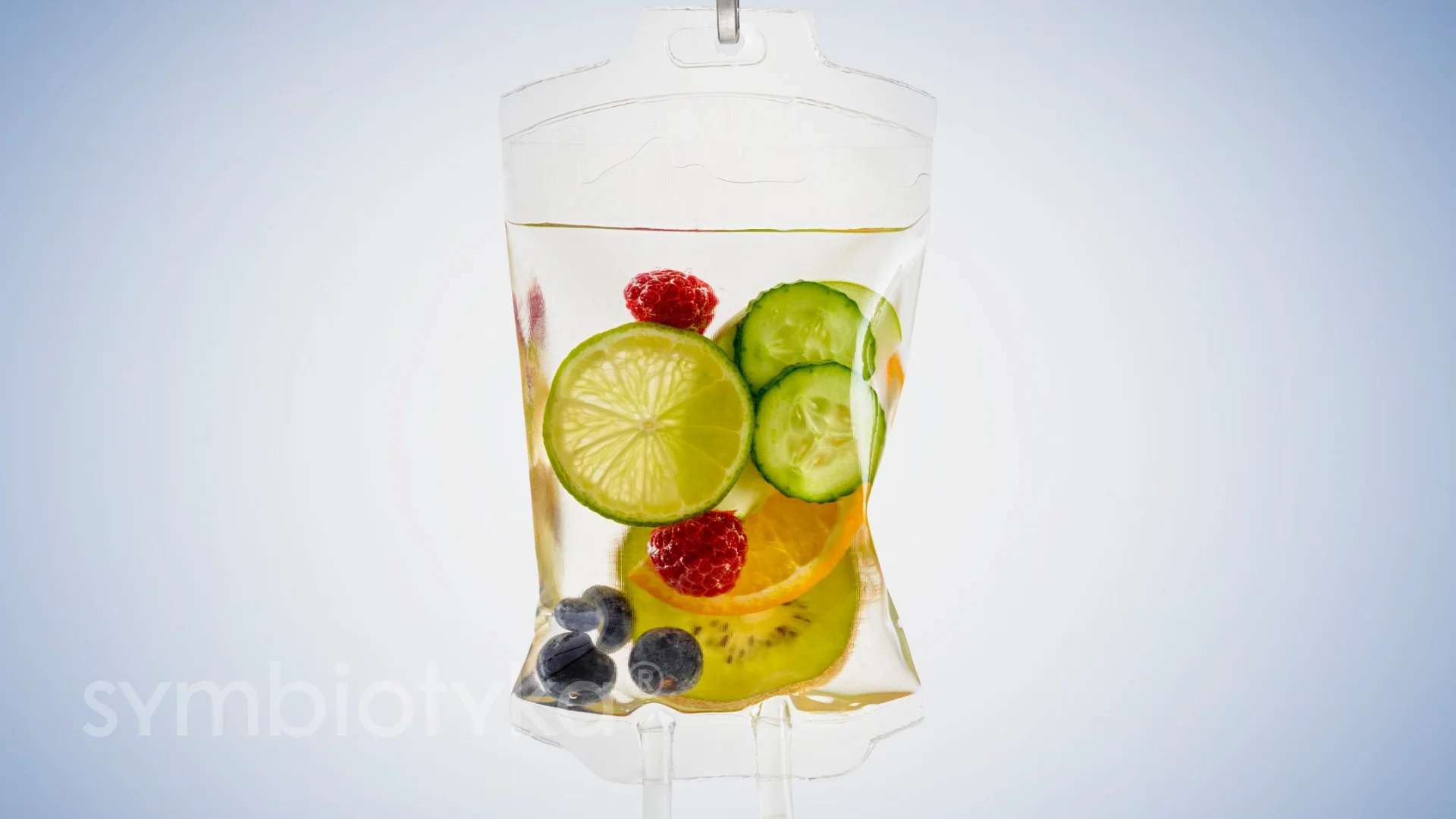 IV bag filled with clear liquid and various fruit slices including lime, cucumber, orange, kiwi, raspberries, and blueberries.