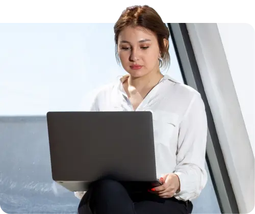 A lady with sitting down facing a laptop.
