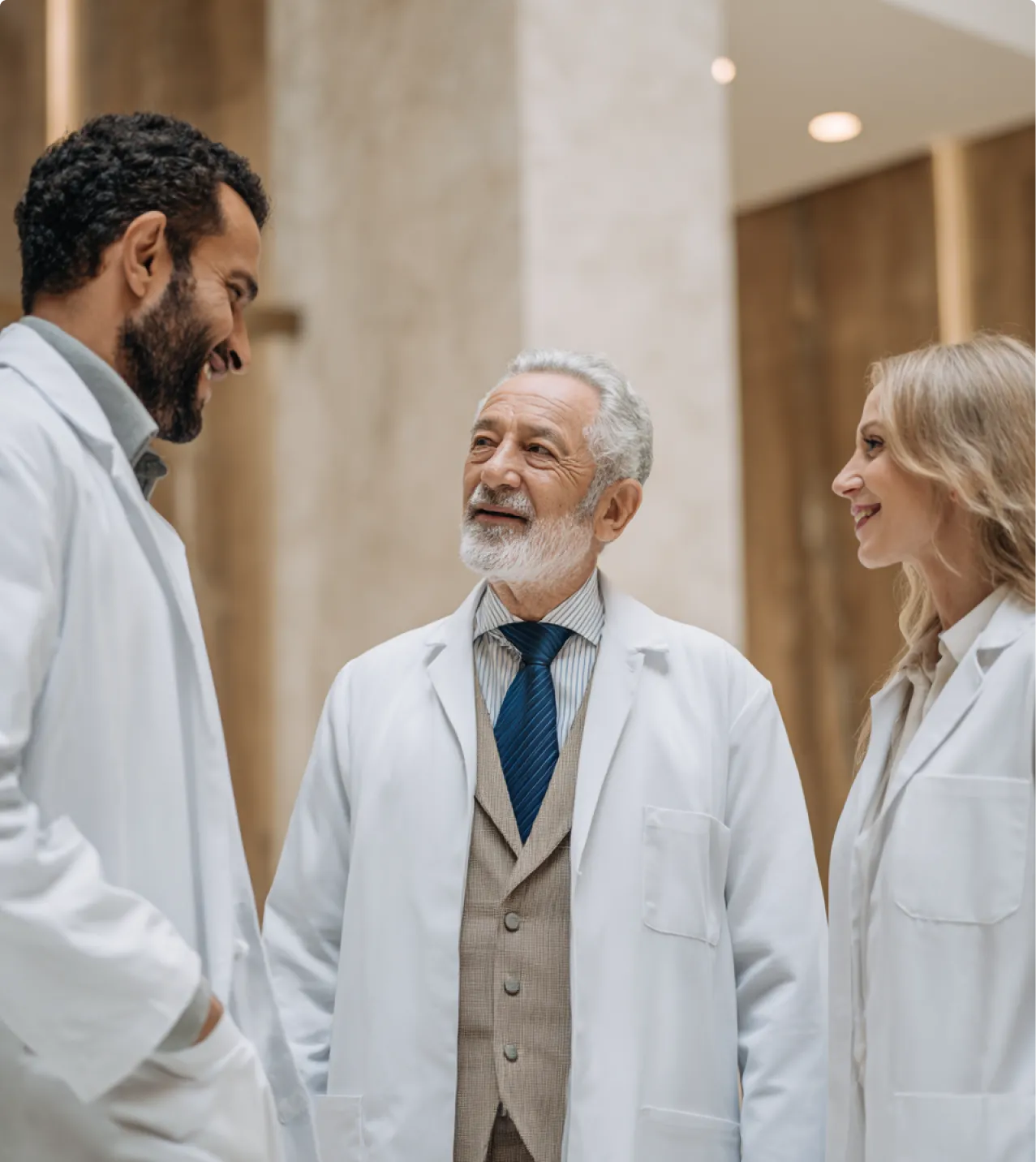 Three doctors standing together and smiling during a conversation.